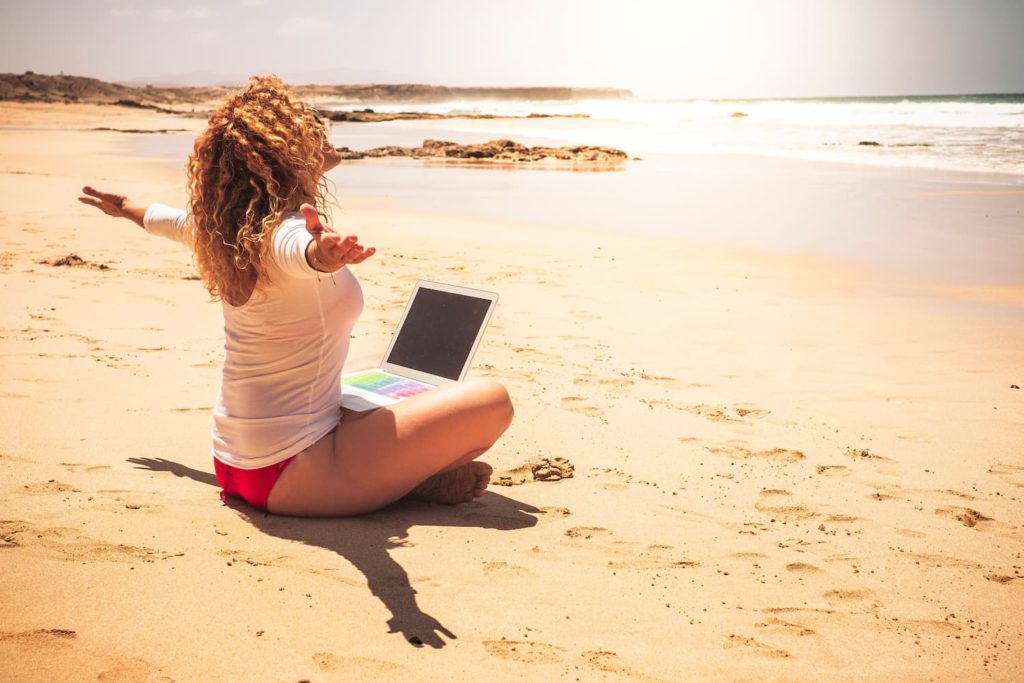 Frau  arbeitet ortsuabhängig mit Laptop am Strand